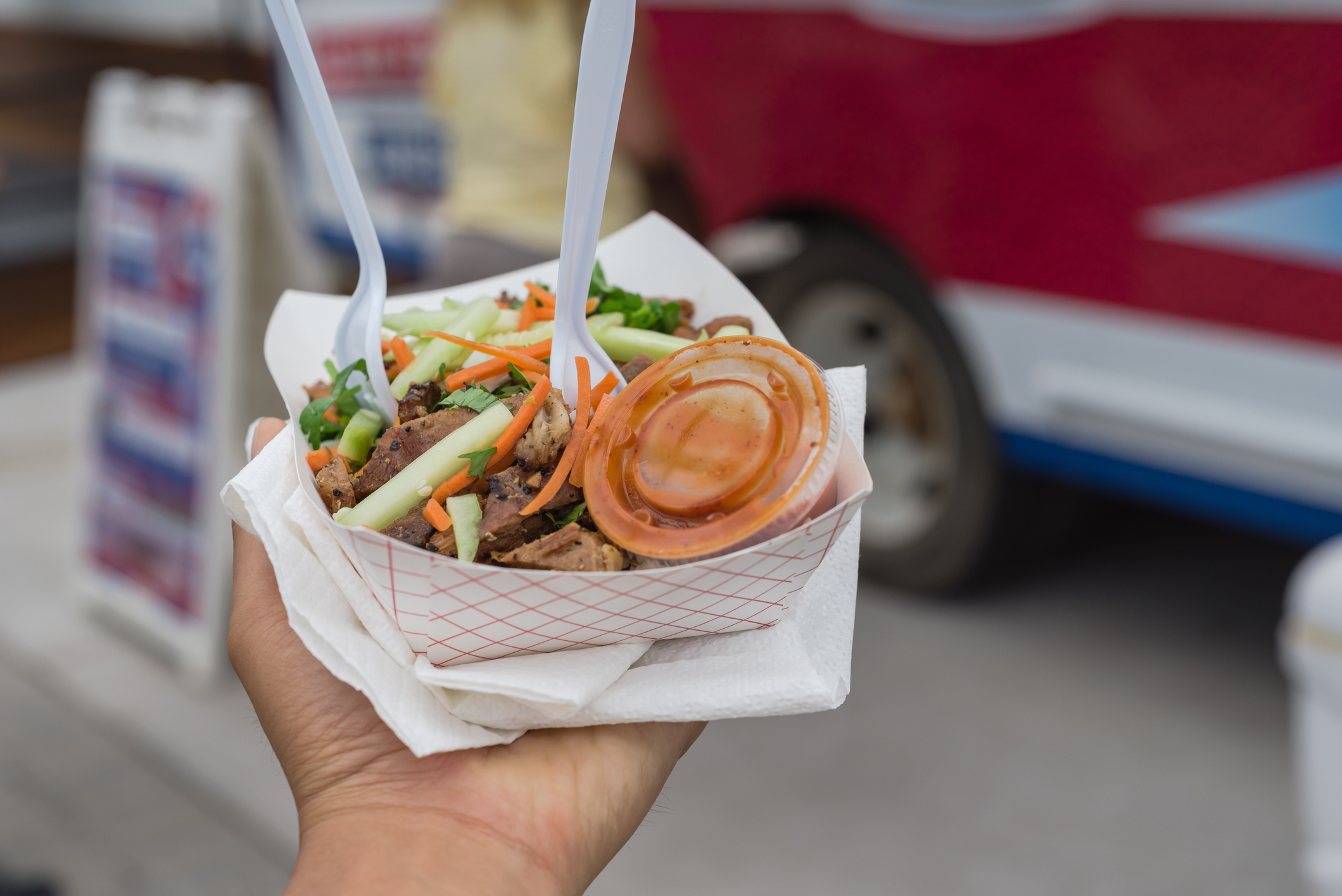 Person holding a plate of food from a food truck festival.