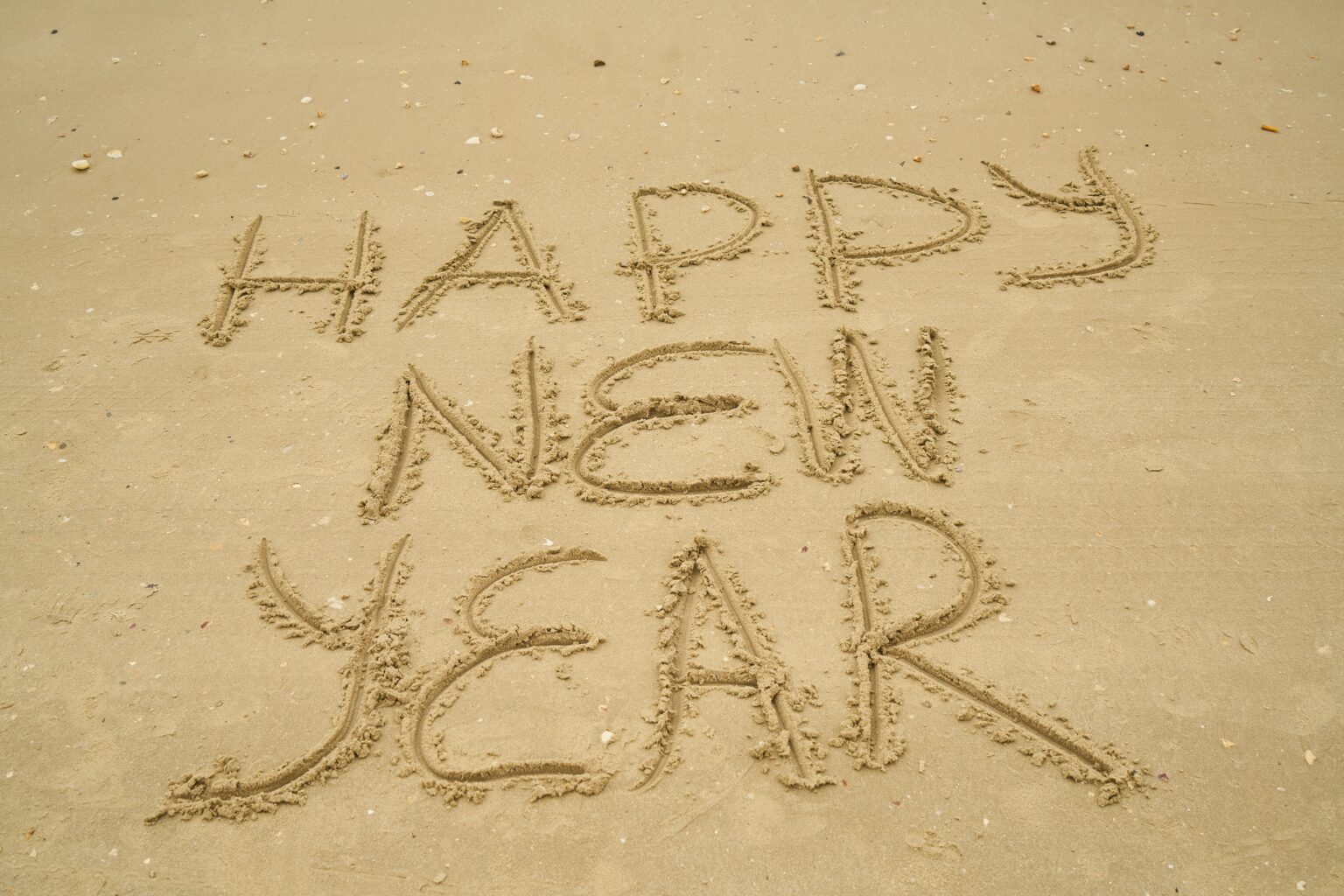 Happy New Year written in the sand at the beach.