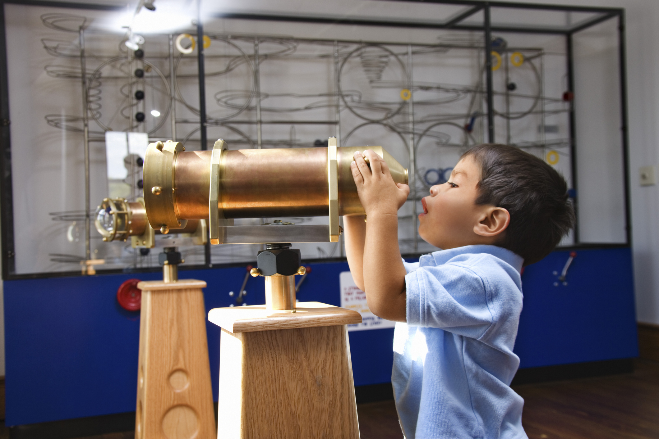 Boy looking through telescope in museum.